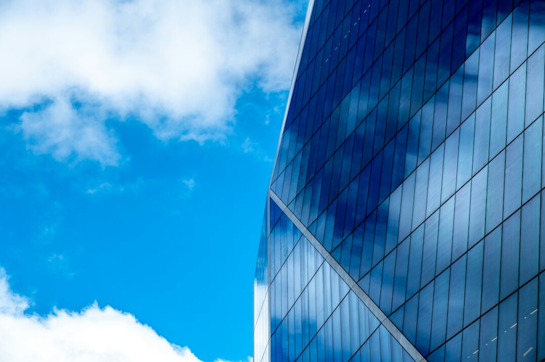 Modern glass office building exterior against blue sky
